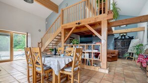 Ein Essbereich mit Holztisch und Stühlen, einer Treppe, einem Bücherregal und einem Fernseher.