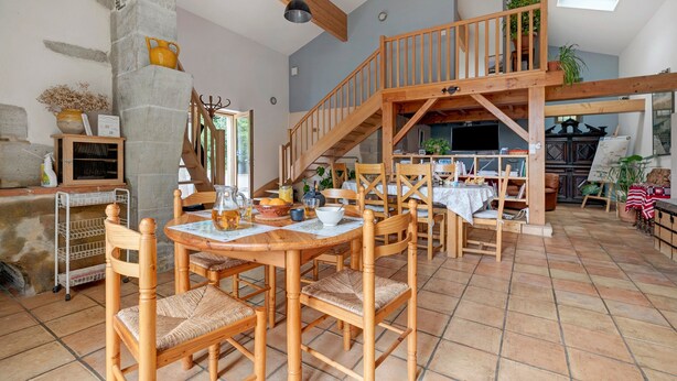 Ein geräumiger Essbereich mit Holzmöbeln und einer Treppe, die in eine obere Etage führt.