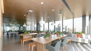 Un espacio de oficina moderno con una mesa de madera alargada, varias sillas y un sofá empotrado.