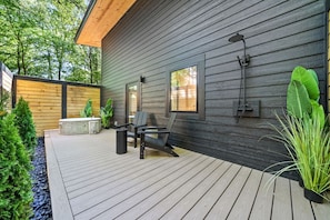 A wooden deck with a seating area, a hot tub, and a large window.
