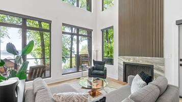 A spacious living room with large windows, a fireplace, and a modern sofa.