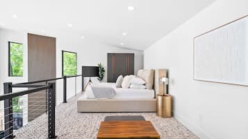 A modern bedroom with a bed, a bedside table, a lamp, and a view of greenery outside.