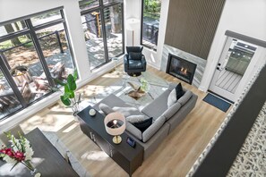 A modern living room with a large window, a fireplace, and a cozy seating area.