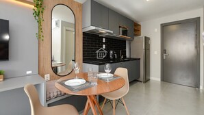 Une cuisine moderne avec des meubles gris, un réfrigérateur en acier inoxydable et un coin repas comprenant une table ronde et des chaises.