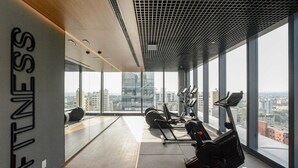 Une salle de sport moderne, dotée d’équipements d’exercice, de grandes fenêtres et offrant une vue sur la ville.