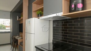 A modern kitchen with a refrigerator, black tiled backsplash, and a window overlooking a cityscape. - Apto Aconchegante Próximo ao Parque Moinhos (Porto Alegre)