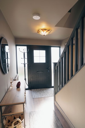 A hallway with a wooden bench, a coat rack, a door, and a staircase. - Ffordd-Y-Wylan by Guestz (Rhosneigr)