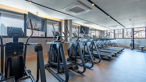 A gym with multiple treadmills, exercise bikes, and a large window with a city view. - Sofisticação e Conforto no Coração do Moinhos (Porto Alegre)