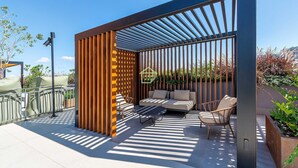 An outdoor seating area with a sofa, chairs, and a table, enclosed by a wooden fence and a metal railing. - Sofisticação e Conforto no Coração do Moinhos (Porto Alegre)