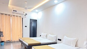 A hotel room with three beds, a ceiling fan, an air conditioning unit, and a door.