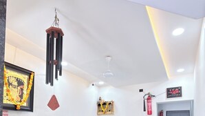 A modern reception area with a counter, a hanging wind chime, a framed picture, and a digital clock.