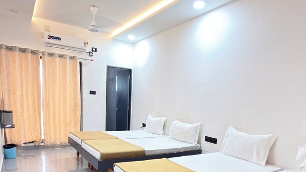 A hotel room with three beds, a ceiling fan, an air conditioning unit, and a door.