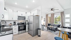 A modern kitchen with white cabinets, stainless steel appliances, and a dining area with a round table and bar stools.