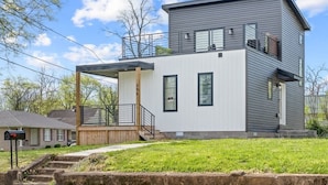 A modern two-story house with a covered porch, a visible garage, and a well-maintained lawn.