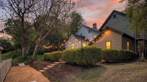 A house with a well-maintained lawn, a wooden deck, and string lights.