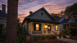 A two-story house with a porch, a chimney, and a tree in the foreground.