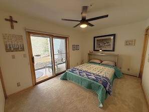 A bedroom with a bed, a ceiling fan, a sliding glass door, and a framed picture on the wall.