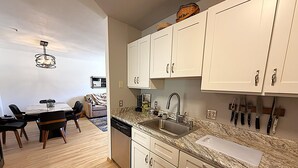 Una cocina moderna con armarios blancos, encimera de granito y lavavajillas empotrado.
