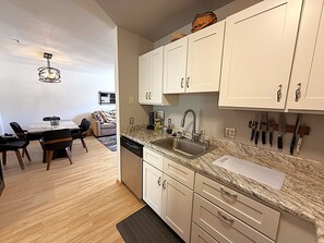 Una cocina moderna con armarios blancos, encimera de granito y lavavajillas empotrado.