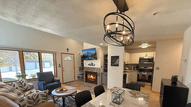 Una sala de estar moderna con chimenea, comedor y cocina.