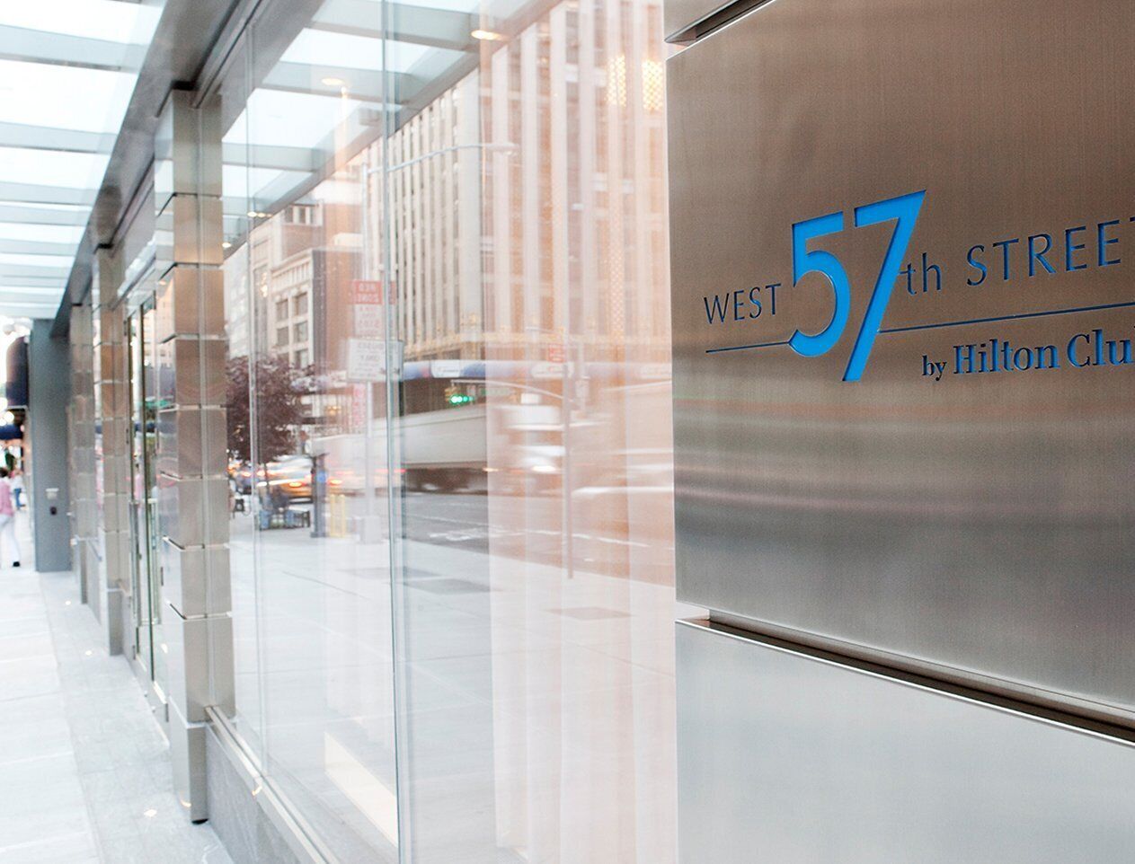 A modern building facade with a glass window and a sign reading "West 57th Street by Hilton Club".