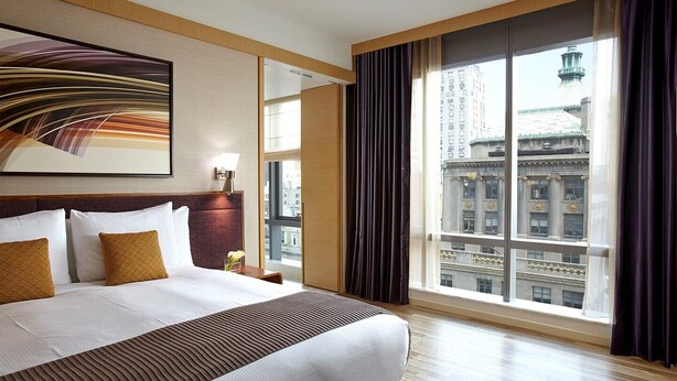 Une chambre d’hôtel dotée d’un grand lit, offrant une vue sur le paysage urbain et présentant un design moderne.
