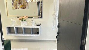 A modern bathroom with a large mirror, a vanity with a sink, a towel rack, and a decorative light fixture. - Modern Apartment Comfortable & Quiet (Santo Domingo Este)