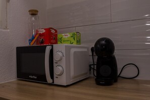 Un microones amb una cafetera i una ampolla a sobre.
