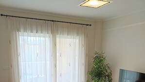 A living room with a sofa, a coffee table, a TV stand, and a potted plant. - Puerto Marina Apartment with Mountain Views, Wi-Fi, and Air Conditioning (Los Alcázares)