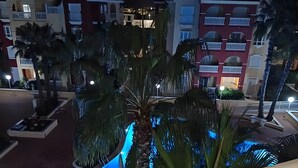A balcony with a railing, palm trees, and buildings in the background. - Puerto Marina Apartment with Mountain Views, Wi-Fi, and Air Conditioning (Los Alcázares)