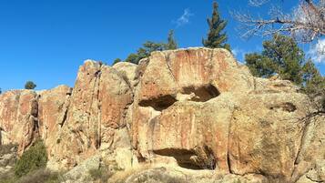 Une vaste formation rocheuse présentant des ouvertures naturelles et une végétation clairsemée.