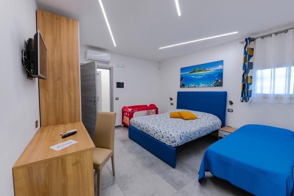 Una habitación de hotel con cama, escritorio, silla, televisor y un cuadro en la pared.