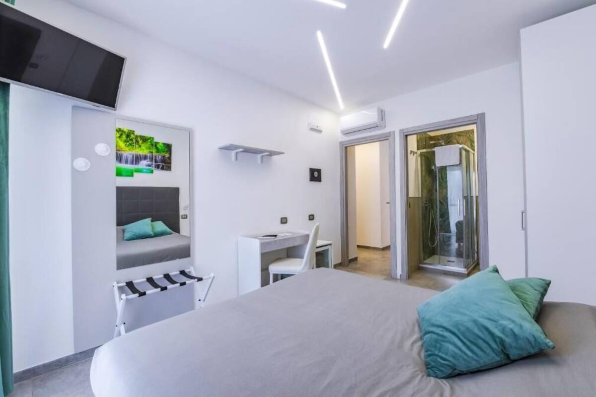 Ein modernes Schlafzimmer mit Bett, Schreibtisch, Stuhl, Fernseher und einer Duschkabine.