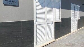 A building with a signboard, two white louvered doors, and a tiled floor. - Aria di Mare (Santa Marinella)