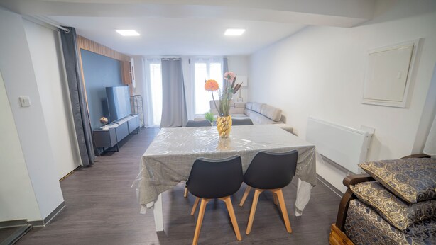 Un salon moderne comprenant une table à manger, des chaises, un téléviseur et un canapé.
