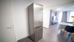 Eine moderne Küche mit einem Edelstahl-Kühlschrank, einem Essbereich mit Tisch und Stühlen sowie einer kleinen Küchenzeile.