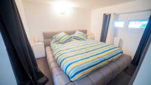 Ein Schlafzimmer mit Bett, Nachttischen und einem Fenster.