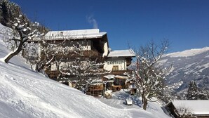 A snow-covered building with a sign reading 'GASTHOF' in a mountainous area. - Gasthof Pension Berghof (Hippach-Schwendberg)