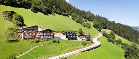 Un hotel con varias edificaciones, un camino sinuoso y una ladera verde.