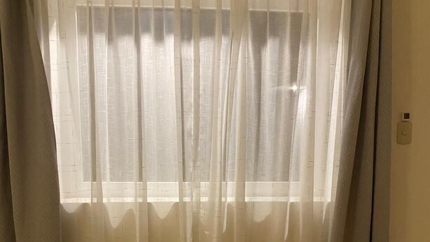 A room with a wooden floor, a window with sheer curtains, and a wooden curtain rod. - Condor Palace (Huayllay)