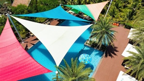 Vista aérea de un resort con piscina, zonas de sombra y palmeras.