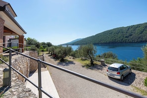 Ein Wohngebiet mit Seeblick, einem geparkten Auto und einer Steinmauer.