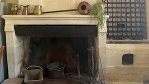 Una chimenea de piedra con repisa, rejilla metálica y hogar de ladrillo.