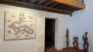 Una habitación con un trabajo artístico en mosaico, esculturas de madera y suelo de baldosas.