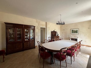 Un comedor con una gran mesa ovalada, sillas de madera, una vitrina de porcelana y un candelabro.