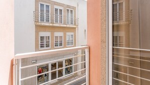 A building with a white facade, a balcony with a metal railing, and a ground-level storefront with mannequins.
