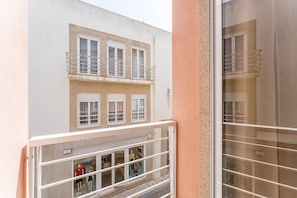 Um edifício com fachada branca, uma varanda com grade de metal e uma loja no térreo com manequins.