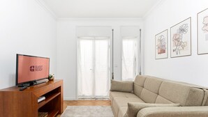 A living room with a TV, sofa, and artwork on the wall.