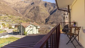 A balcony with a view of a mountain, a small table with a chair, and a potted plant. - Wonderful three-room apartment in the mountains: comfort and relaxation for families/groups, bbq (Montescheno)