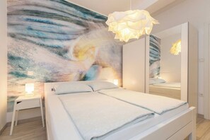 A bedroom with a bed, bedside tables, a wall painting, a mirror, and a hanging light fixture. - 209 Sea Side 2Bedrooms Holiday Apartment  seaview (Duga Luka)